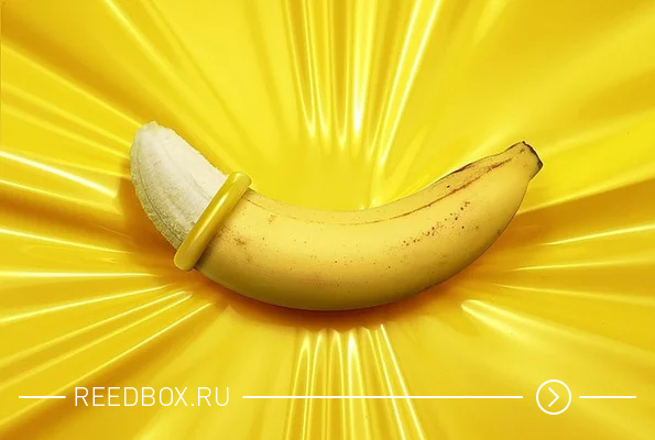Банан в презервативе на желтом фоне